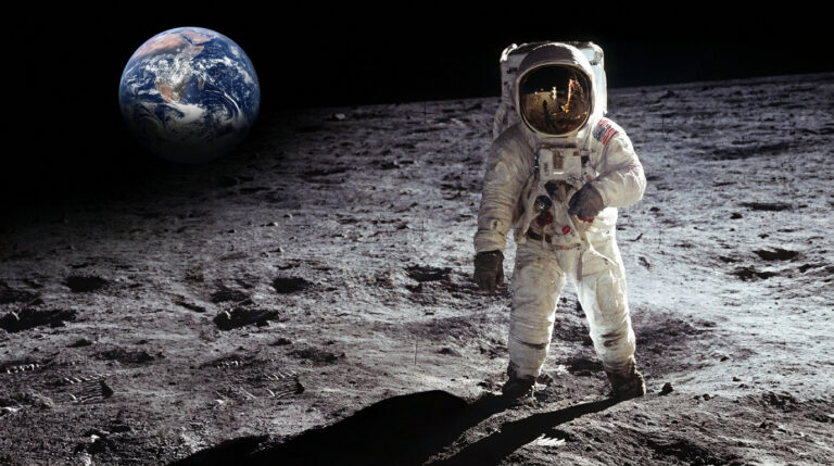 Astronaute sur la Lune, combinaison blanche, drapeau US visible. La Terre est à gauche dans le ciel noir. Surface lunaire grise, roches, ombres.